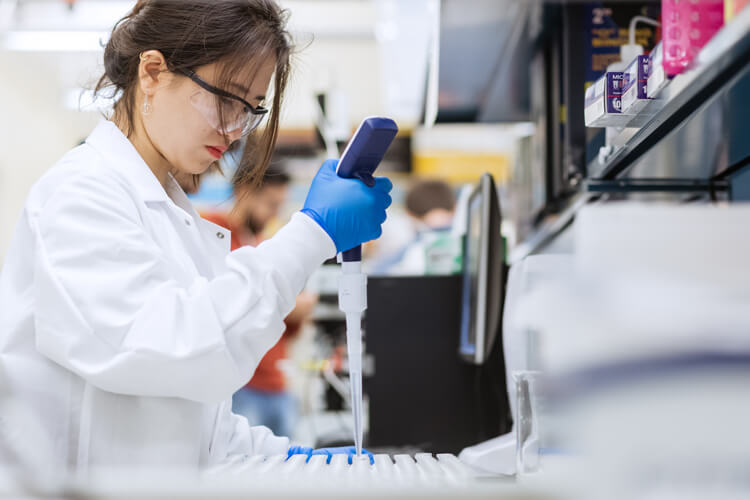 Student in a white lab coat doing biochemistry research.