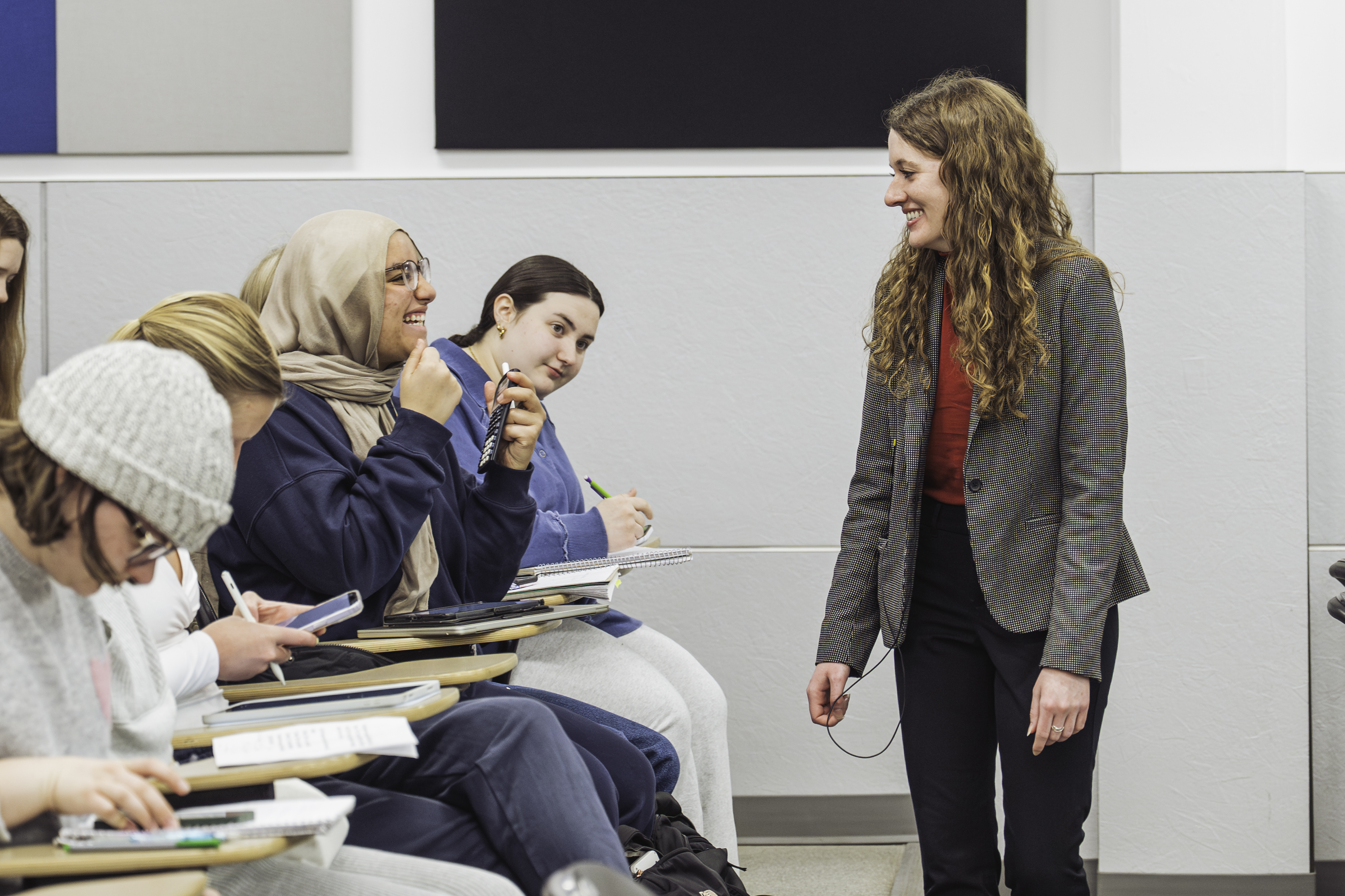 Hannah Starr smiles while engaging with students seated in a university classroom.
