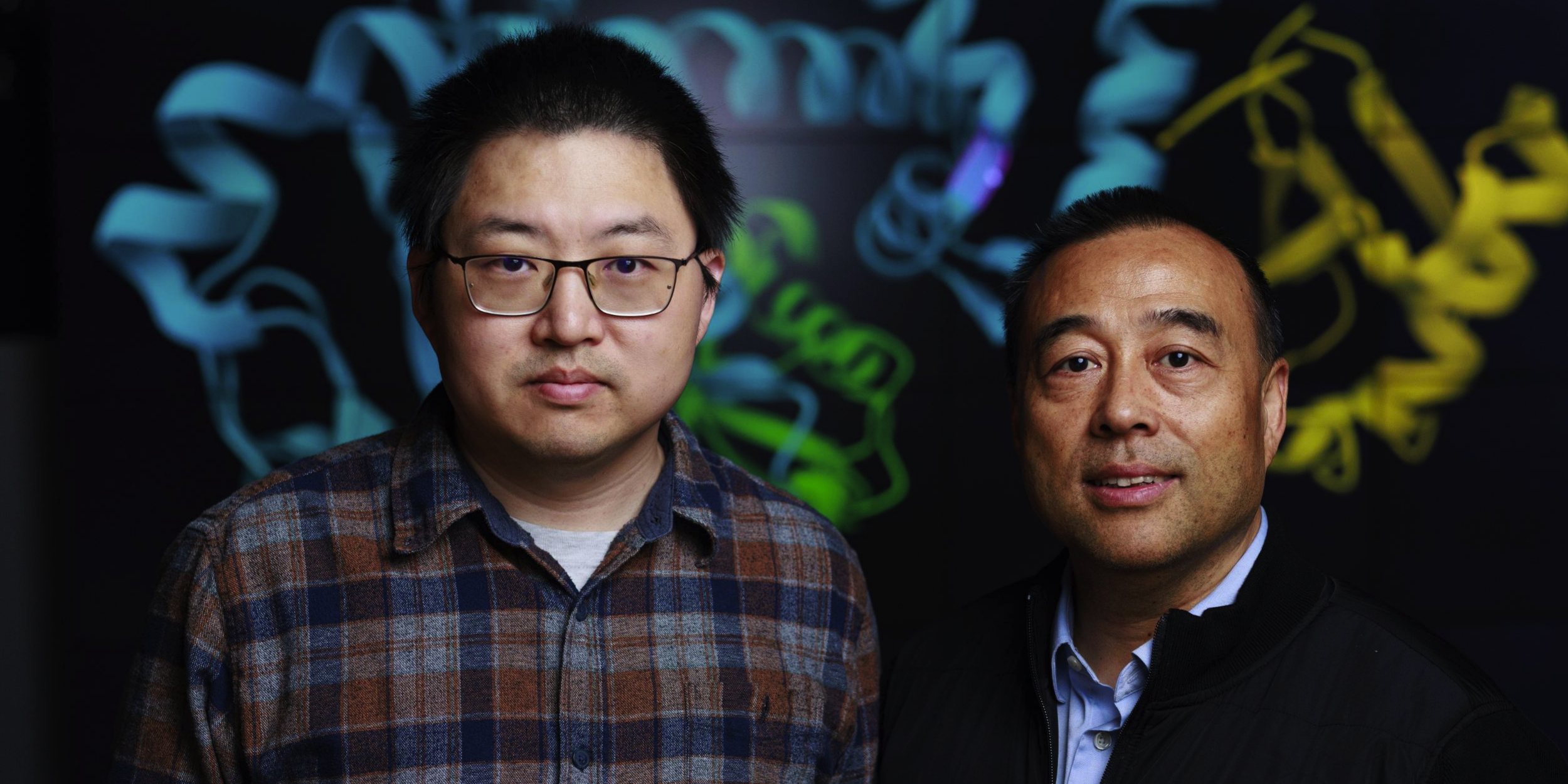 Purdue University researchers Ming Chen and Guang Lin pose in front of a colorful protein structure visualization.