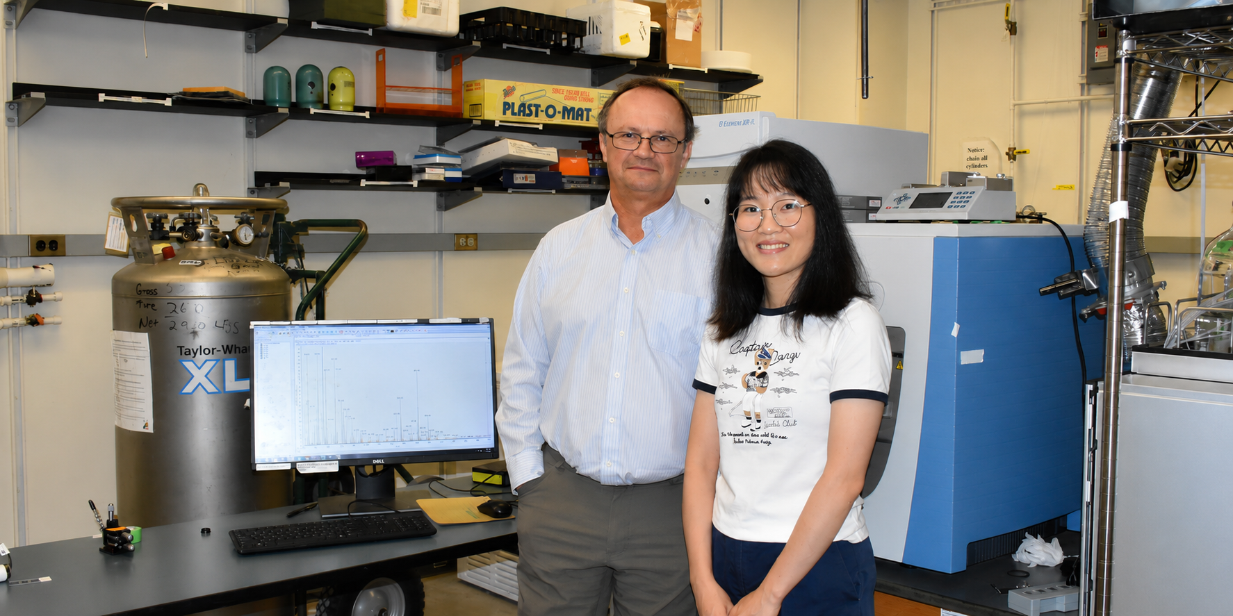 Alexander Laskin and Qiaorong Xie stand in front of a mass spectrometer in Laskin's lab, where they study atmospheric aerosol particles.
